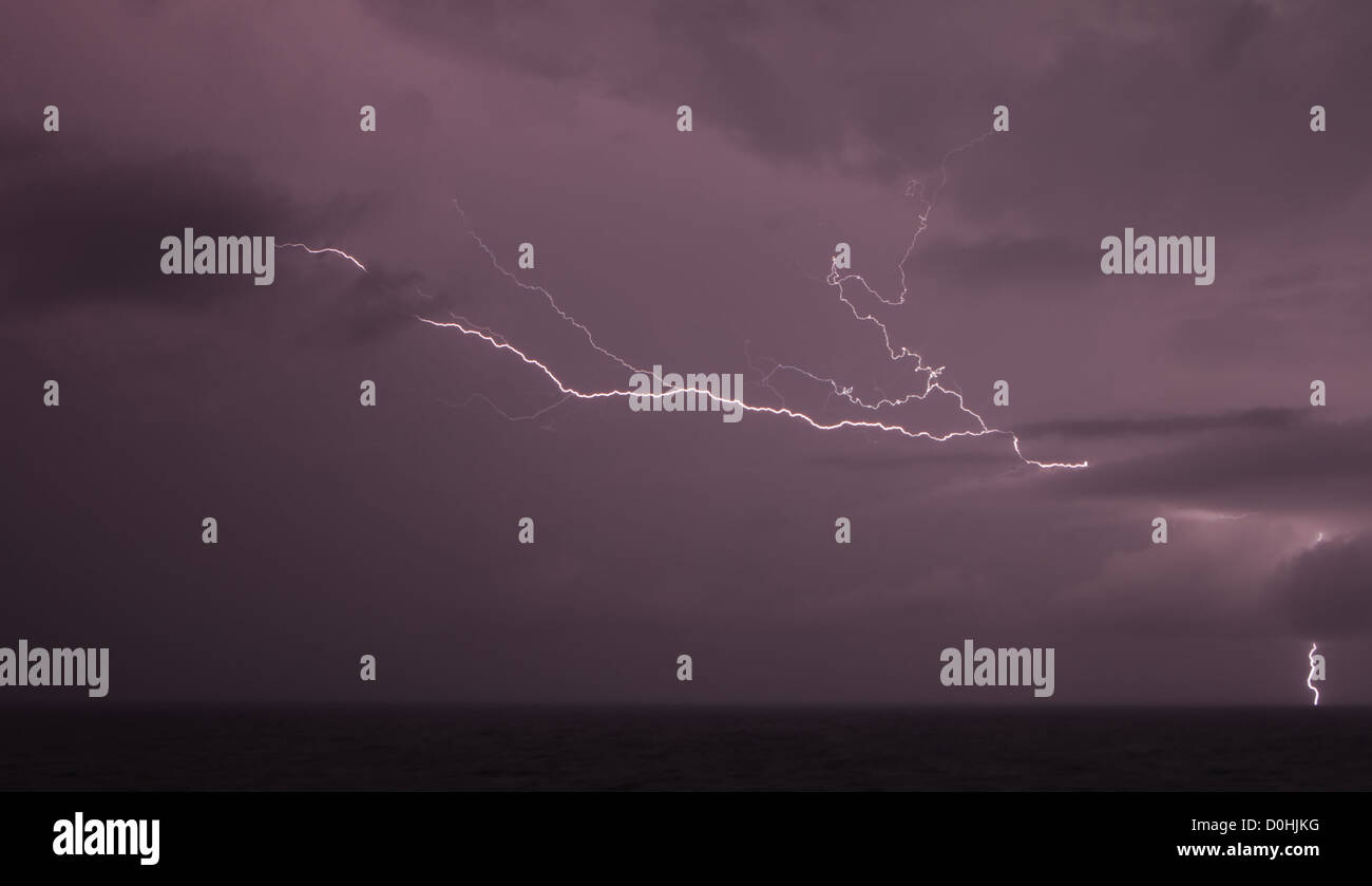 Beleuchtung flackert zwischen Wolken und Einleitungen ins Meer während eines heftigen Gewitters. Stockfoto