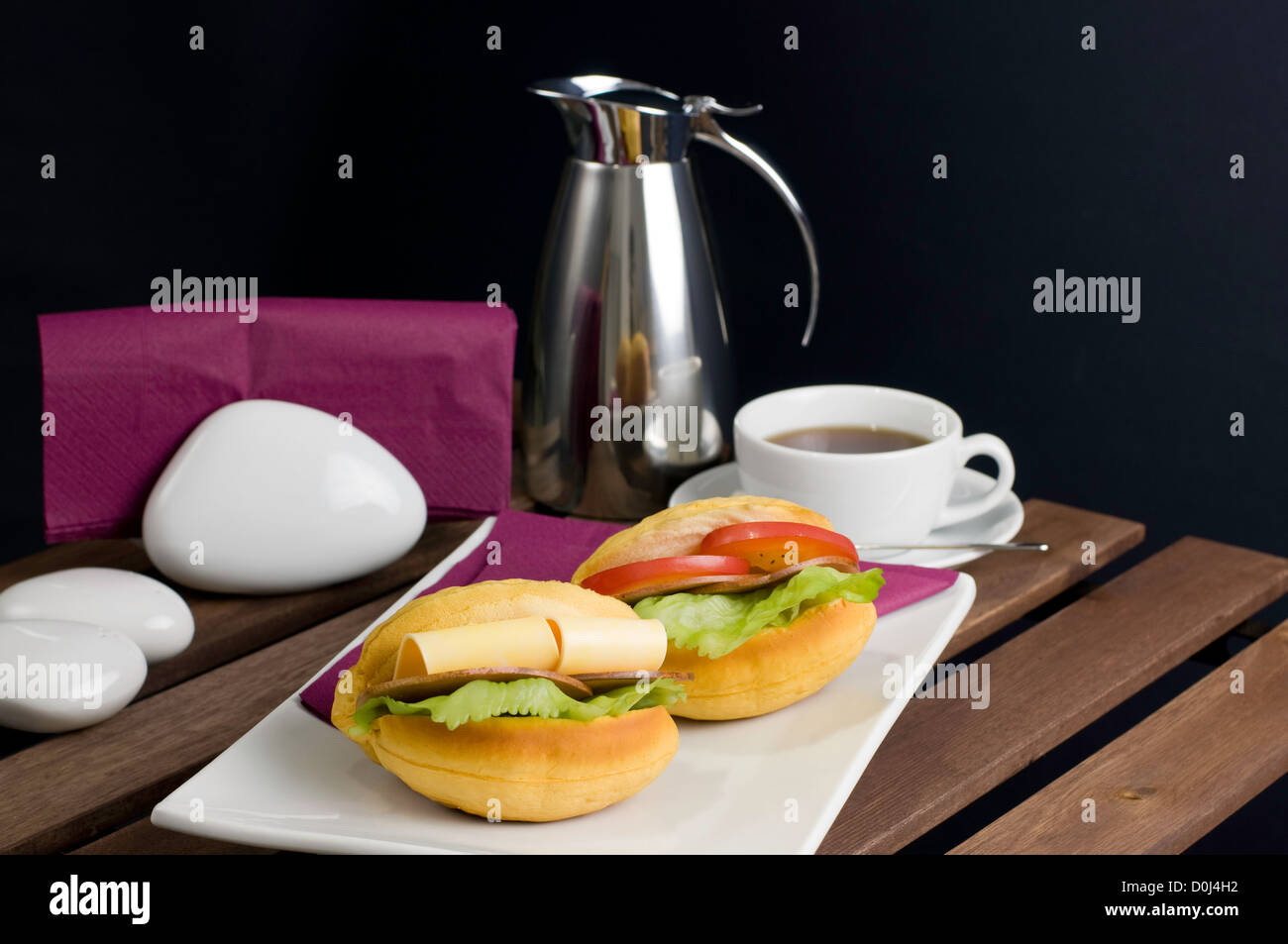 Zwei Sandwich auf weißen Porzellanteller, Tasse Tee und Thermoskanne auf Tisch Stockfoto