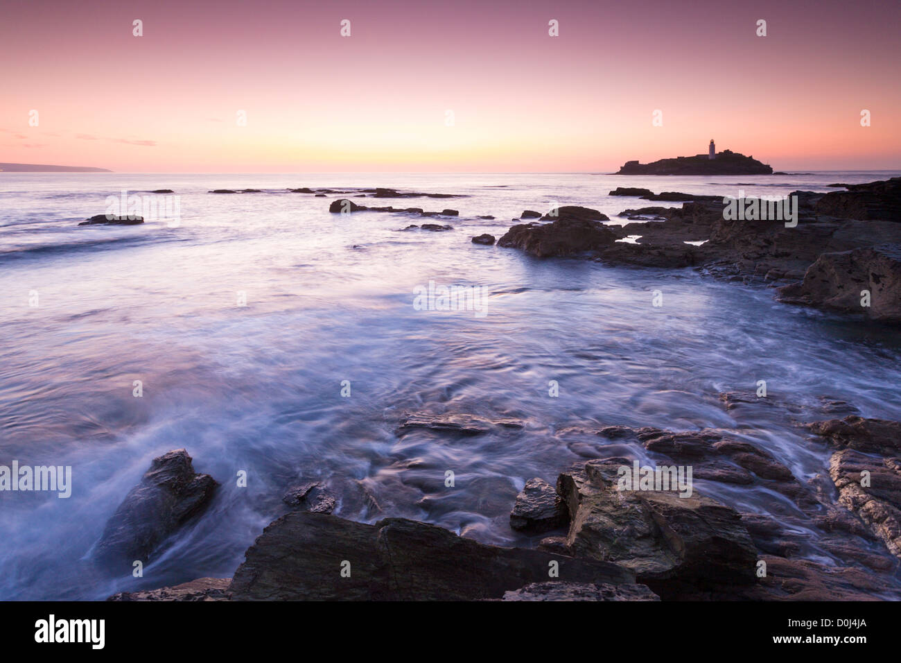 Kollision mit Felsen bei Sonnenuntergang, Godrevy Leuchtturm, Küste Cornwalls Meerwasser Stockfoto