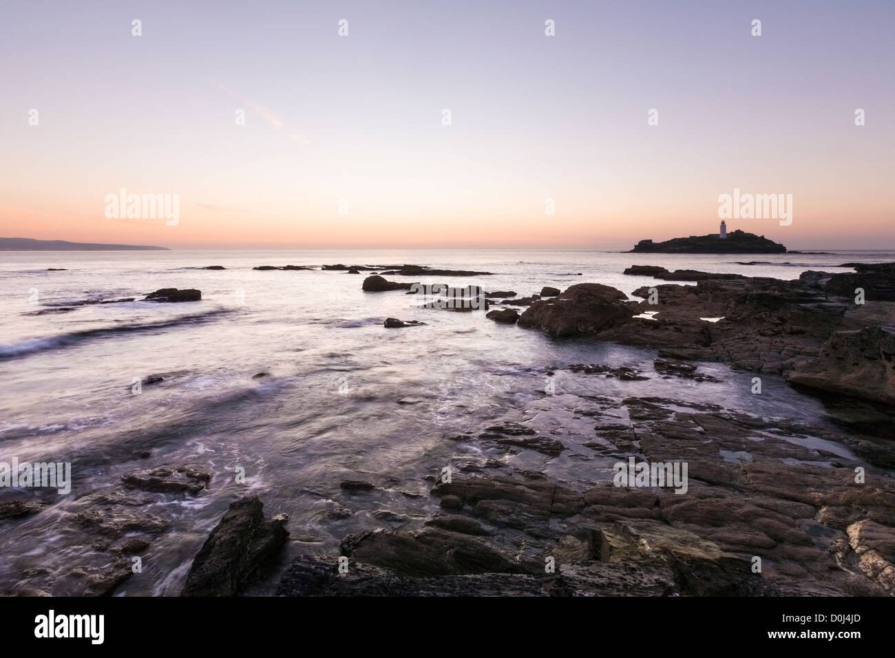 Kollision mit Felsen bei Sonnenuntergang, Godrevy Leuchtturm, Küste Cornwalls Meerwasser Stockfoto