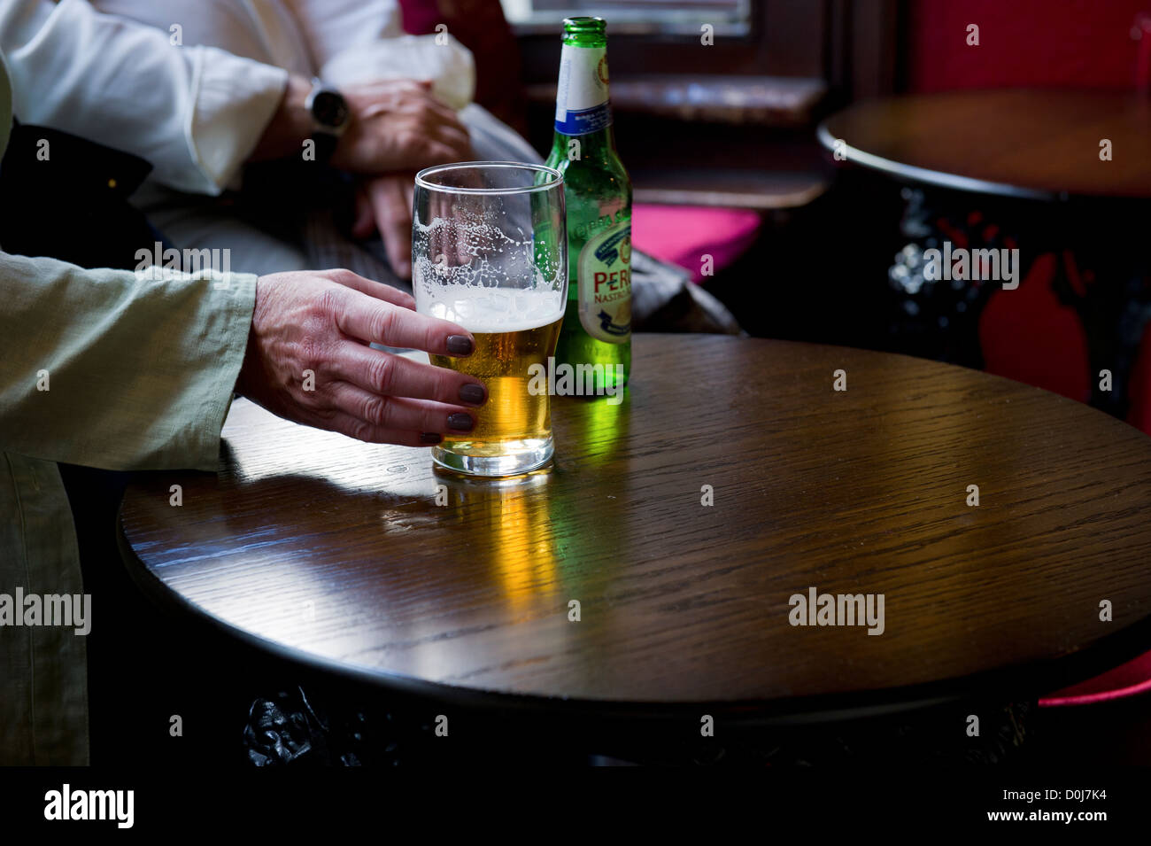 Eine Hand greift nach einem Glas Bier in einem Pub. Stockfoto