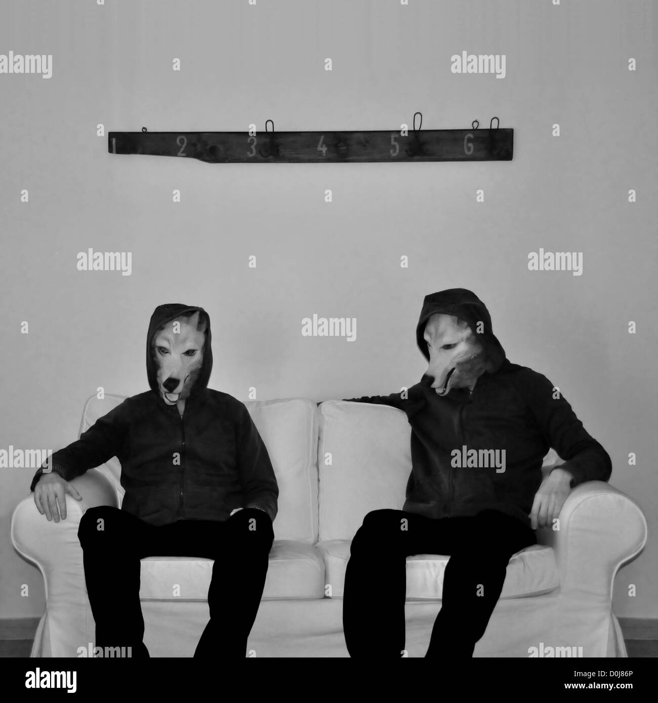 Zwei Figuren mit Hundemaske auf Couch sitzen. Schwarz und weiß. Stockfoto