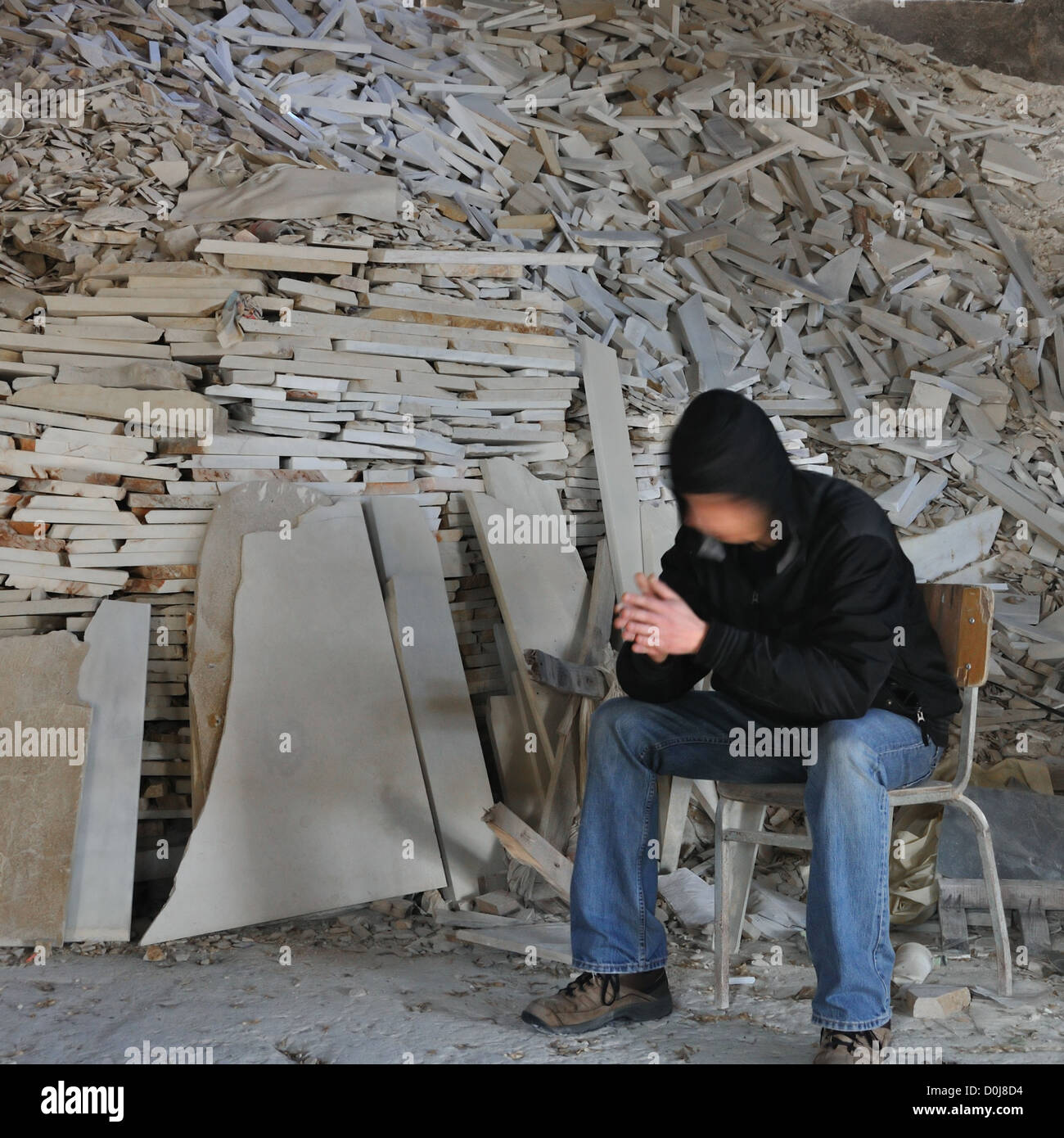 Bewegung verwischt Mann sitzt neben einem Haufen von Marmorfragmenten in verlassenen Inneren. Stockfoto