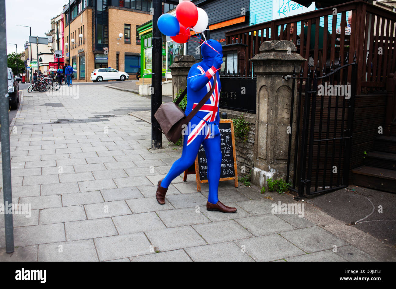 Ein Mann, gekleidet in einem Union Jack-Kostüm trägt Ballons auf Whiteladies Straße in Bristol. Stockfoto