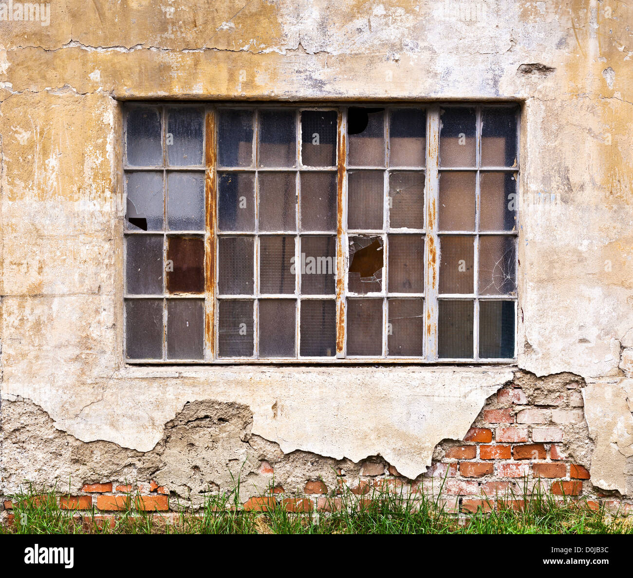 Ein großes Fenster mit zersprungenen Fensterscheiben an der Wand eines heruntergekommenen Altbaus Stockfoto