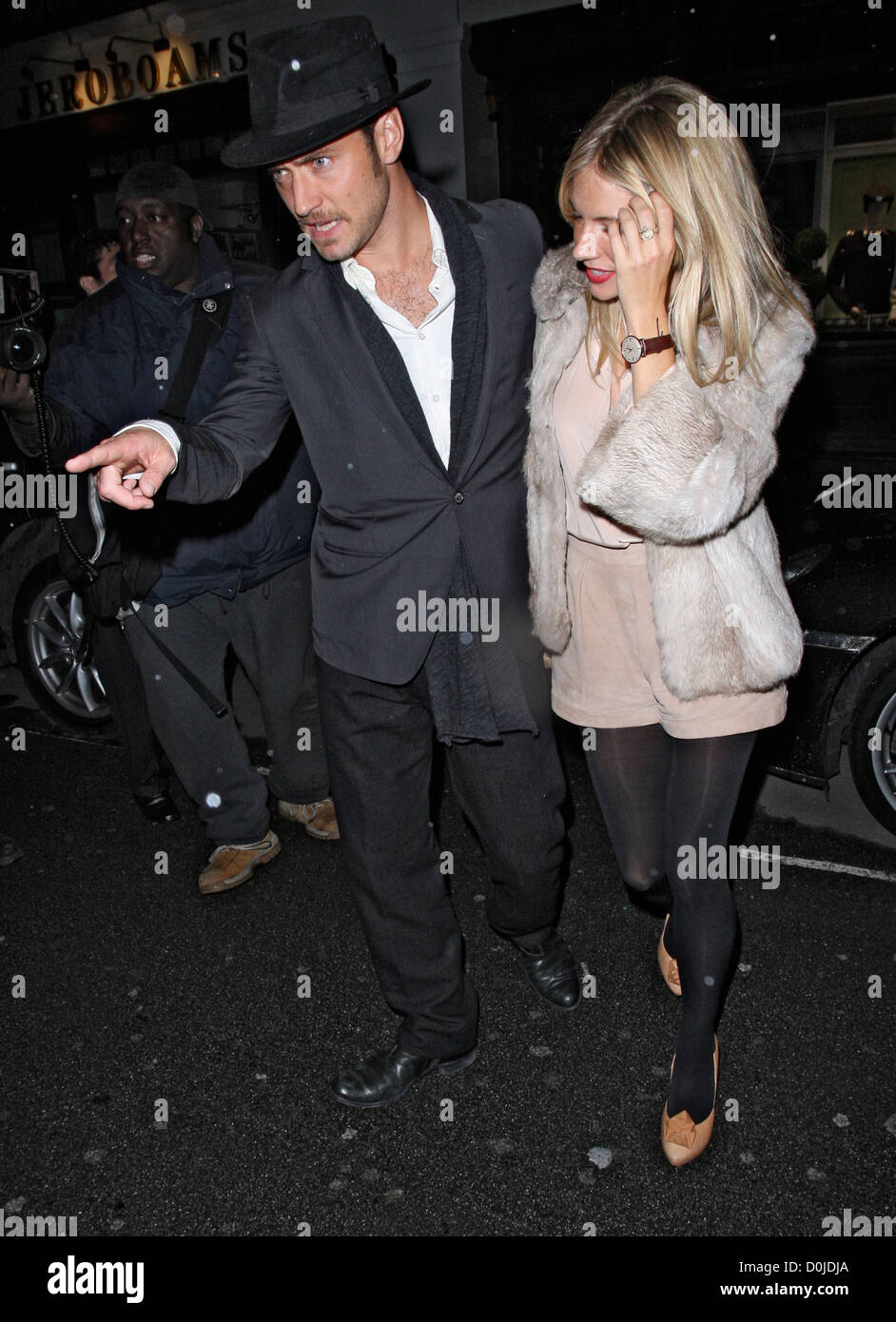 Jude Law und Sienna Miller verlassen C Londoner Restaurant. Sienna trug einen Pelzmantel, leuchtend roten Lippenstift und grauen Nagellack Stockfoto