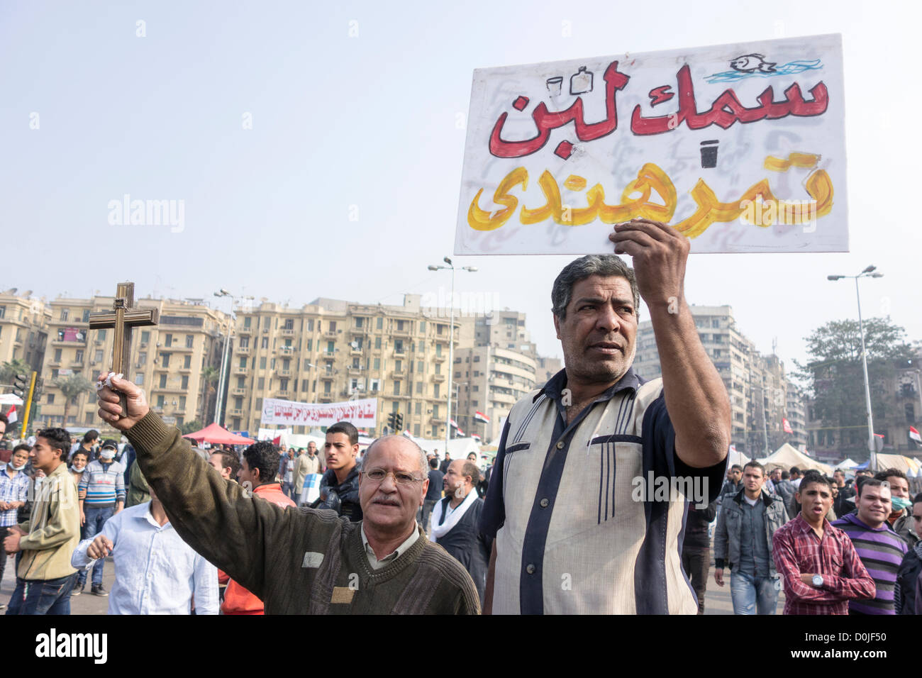 27. November 2012. Demonstranten protestieren gegen Präsident Morsi Annahme der absoluten Mächte auf dem Tahrir-Platz, hält Kairo eine ein Schild in arabischer Sprache, das bedeutet "Die Dinge sind ein totales Durcheinander" ein anderes hält ein Kreuz in Solidarität. Stockfoto