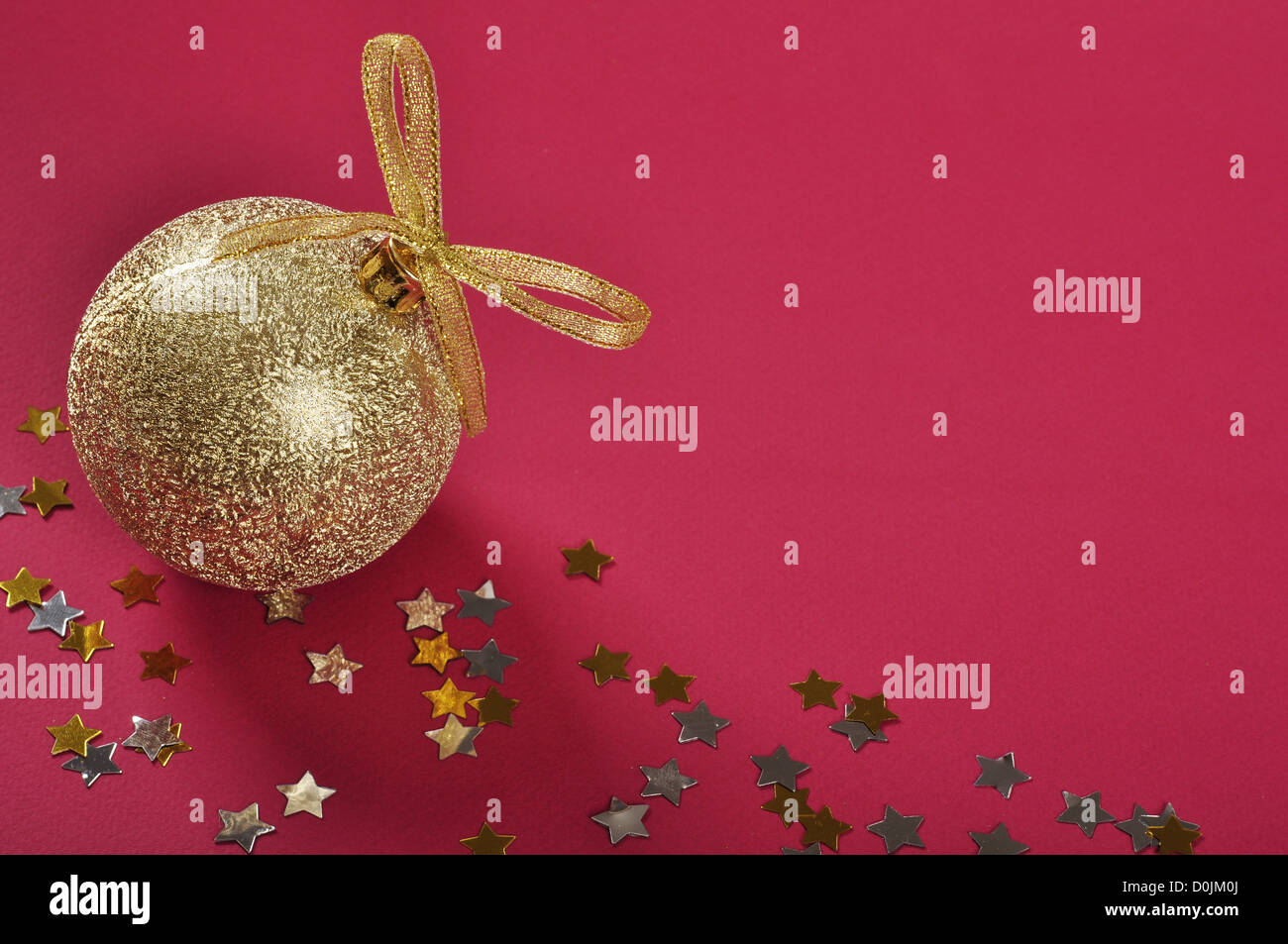 Goldglitter Weihnachtskugel mit Schleife und Bogen über rotem Grund. Stockfoto