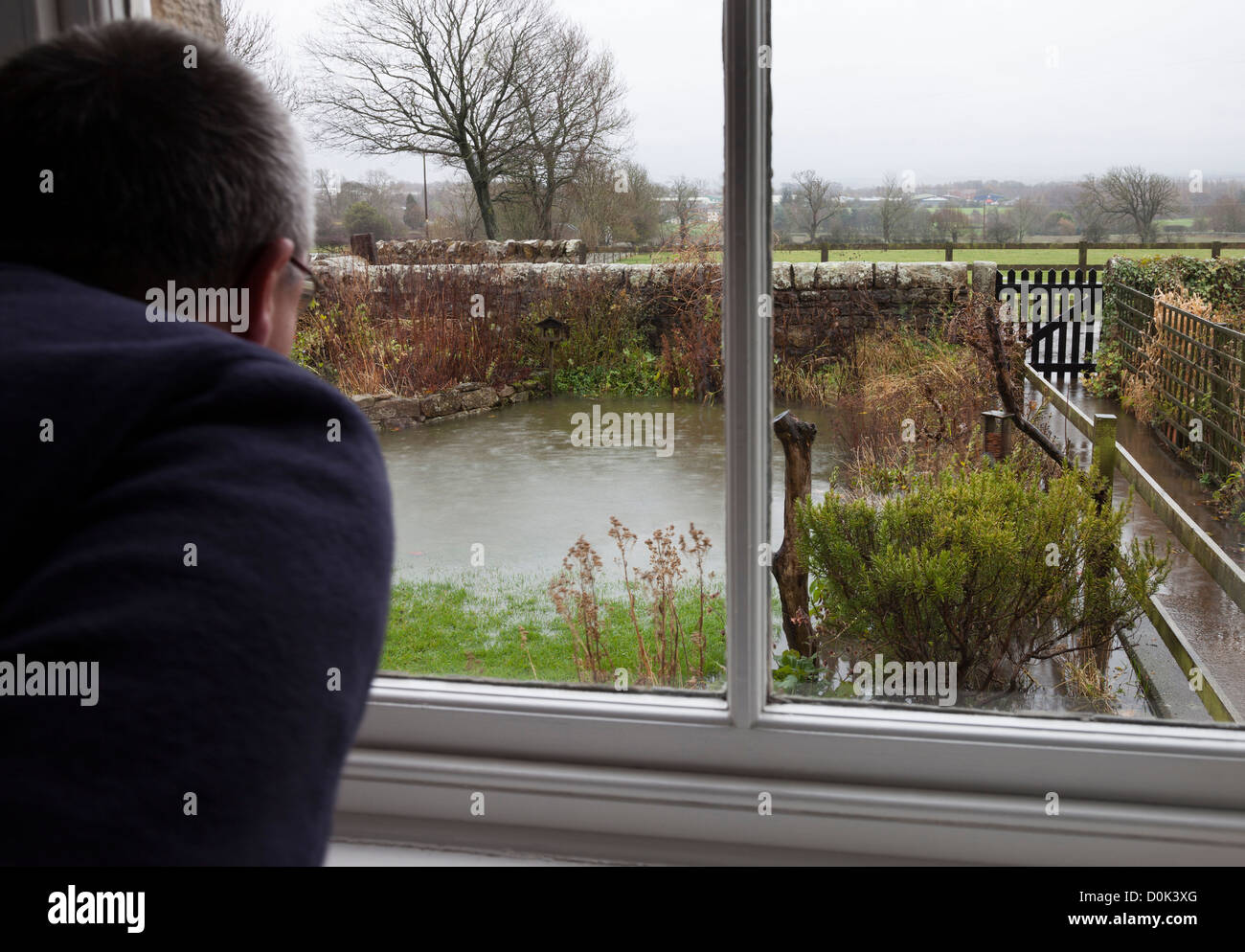 Betreffenden Haushaltsvorstand Blick aus dem Fenster auf steigende Flutwasser in ihrem Garten, County Durham, England UK Stockfoto