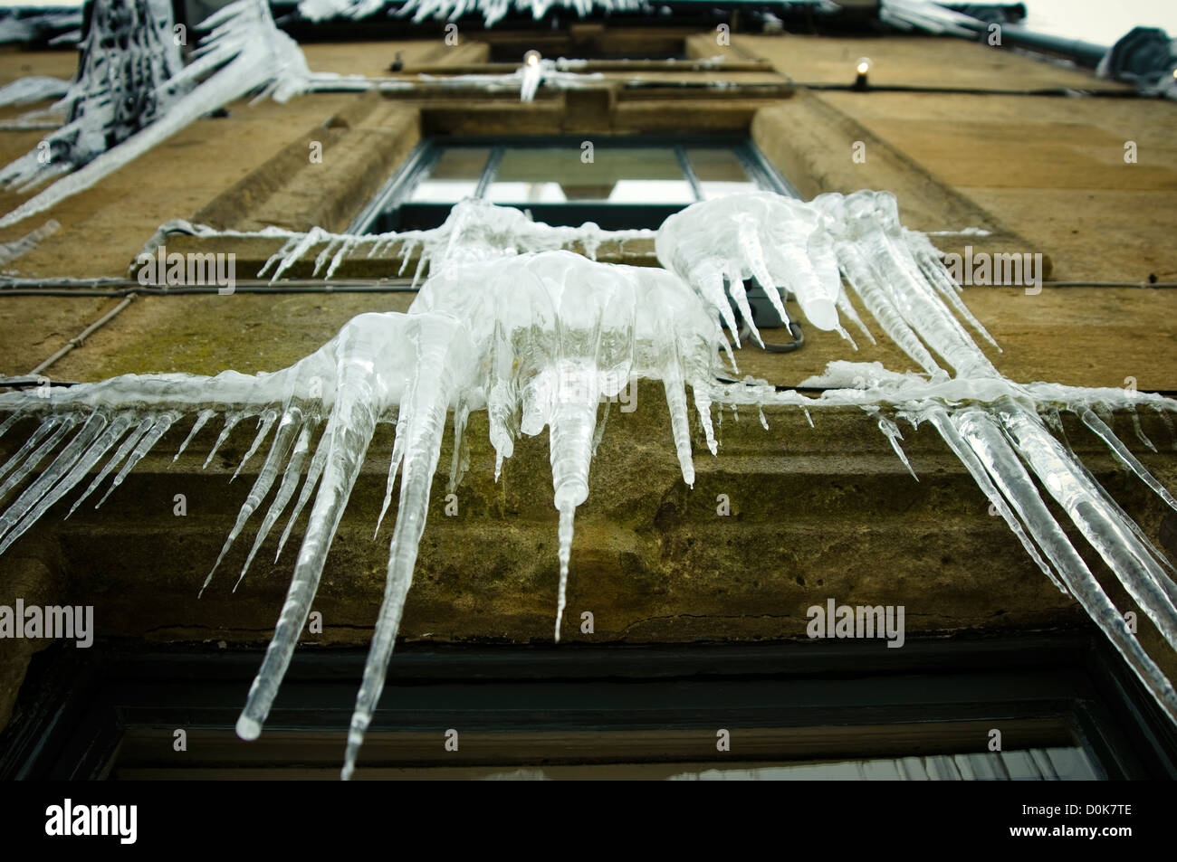 Eiszapfen hängen von einem Pub-Fenster. Stockfoto