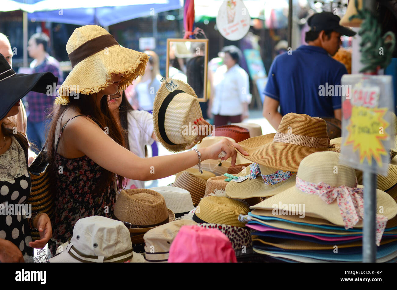 Eine Frau betrachtet man Hüte am Chatuchak-Markt in Bangkok, Thailand. Stockfoto