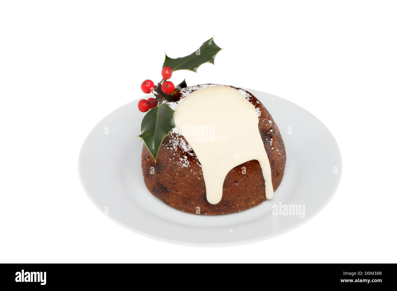 Christmas Pudding mit Sahne garniert und dekoriert mit Holly auf einer Platte isoliert gegen weiß Stockfoto