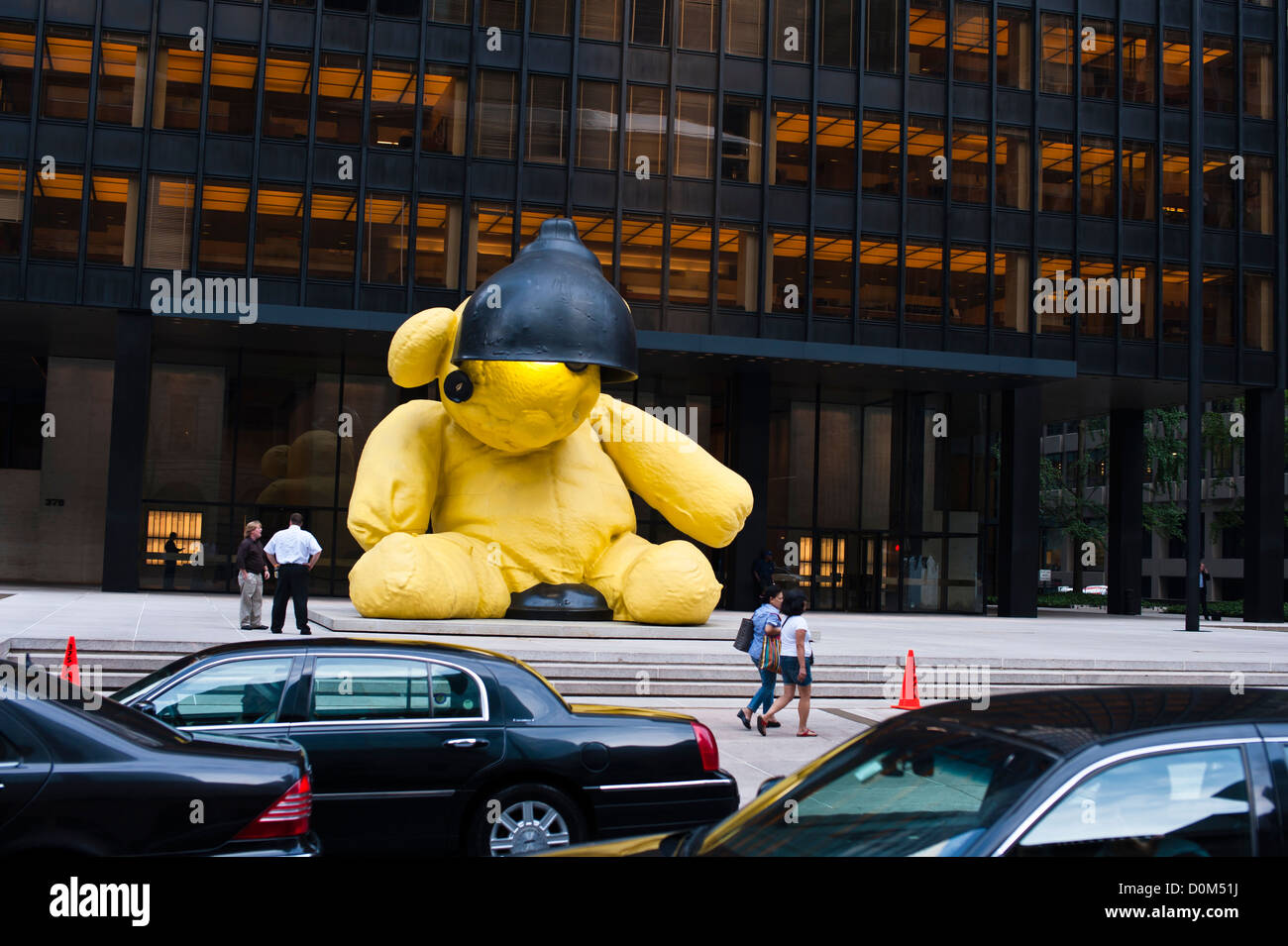 Ein riesiger Teddybär sitzt auf dem Bürgersteig vor einem Städtebau blickte auf eine Flotte von Limousinen in Manhattan. Stockfoto