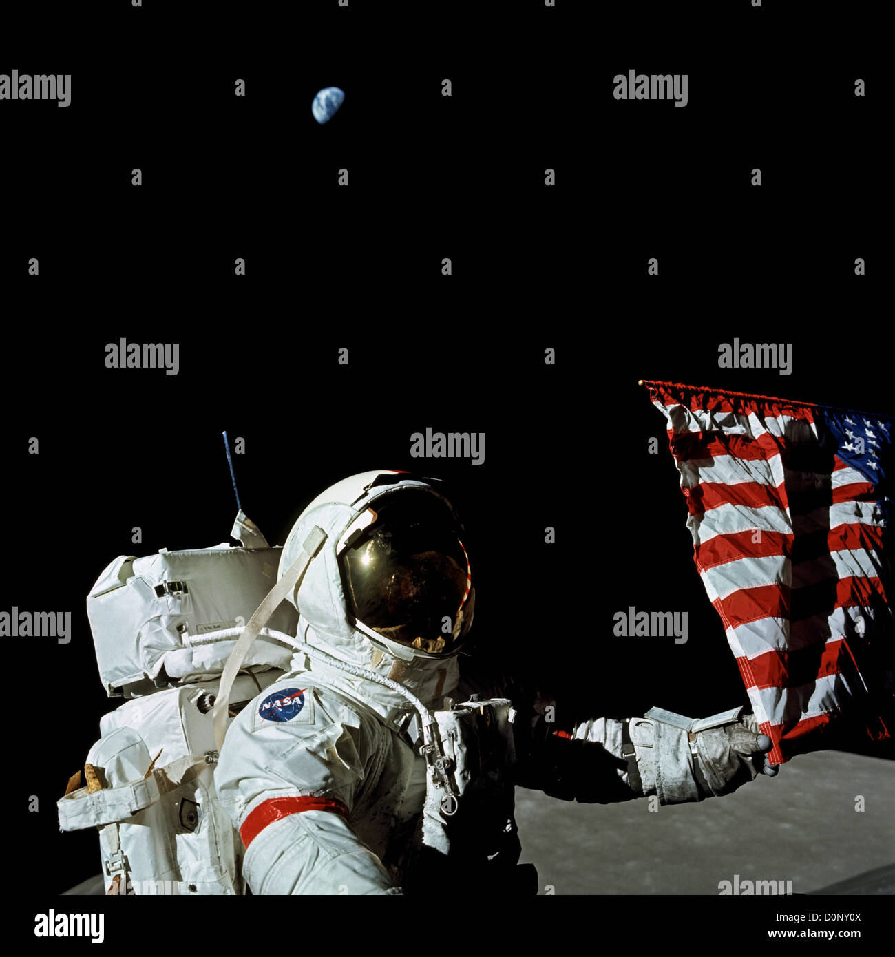 Ein Astronaut der Apollo 17 steht in der Nähe eine amerikanische Flagge, wie die Erde Overhead hängt Stockfoto