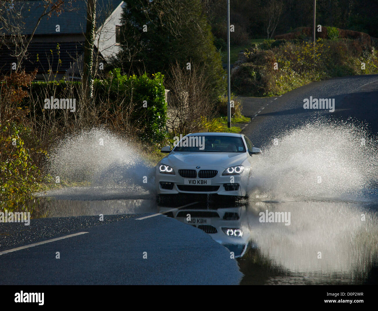 Auto durch stehendes Wasser auf der überfluteten Straße, Cumbria, England UK Stockfoto