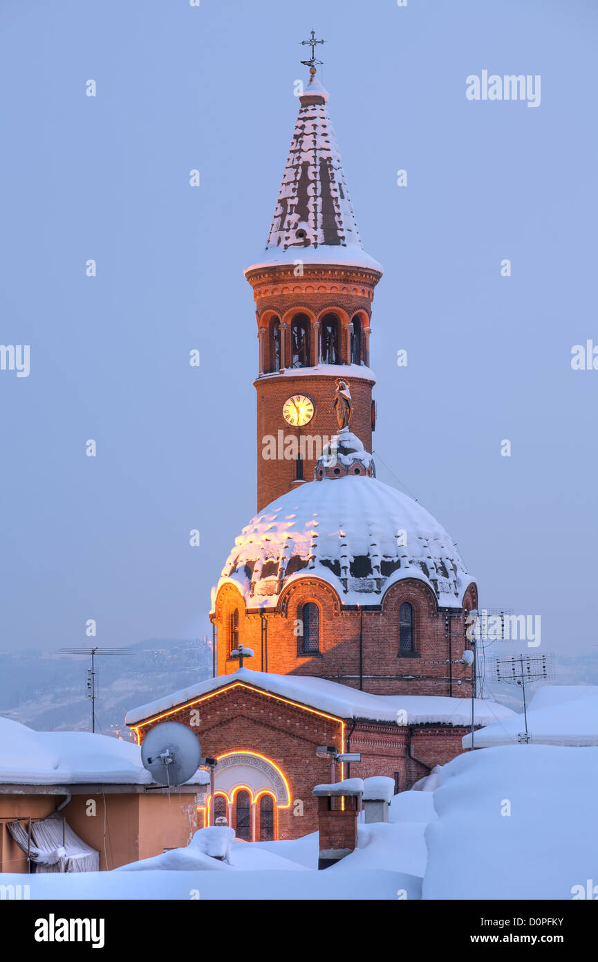 Vertikal ausgerichtete Bild der katholischen Kirche Kuppel und Glockenturm am Abend in Alba, Norditalien mit Schnee bedeckt. Stockfoto