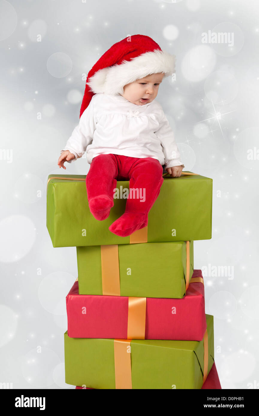 Baby sitzt auf einem Stapel von Weihnachten präsentiert, Bokeh Hintergrund Stockfoto