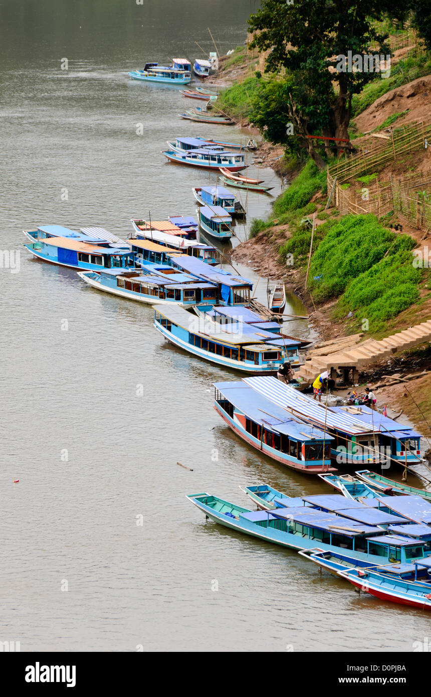 Boote entlang der Flussufer Nong Khiaw Laos // NONG KHIAW, Laos — zahlreiche Boote liegen an der Uferpromenade der Stadt in Nong Khiaw im Norden Laos. Diese Aufnahme, aufgenommen von der hohen Brücke, die den Fluss überspannt, bietet einen erhöhten Blick auf die Uferpromenade. Stockfoto Boote entlang der Flussufer Nong Khiaw Laos // NONG KHIAW, Laos — zahlreiche Boote liegen an der Uferpromenade der Stadt in Nong Khiaw im Norden Laos. Diese Aufnahme, aufgenommen von der hohen Brücke, die den Fluss überspannt, bietet einen erhöhten Blick auf die Uferpromenade. Stockfoto