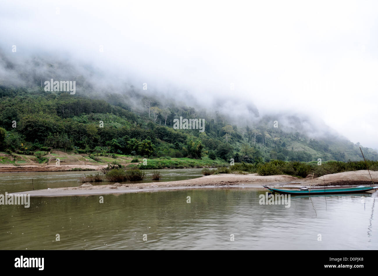 Nam-ou-Fluss Karst Landschaft Nong Khiaw Laos // NONG KHIAW, Laos — Nebel umhüllen die steilen Kalksteinkarste entlang der Ufer des Nam-ou-Flusses in Nong Khiaw im Norden Laos. Sandbänke in der Mitte des Flusses bilden kleine Sandinseln und geschützte Anlegeplätze für lokale Boote. Der Nam Ou, auch bekannt als Fluss Ou, fließt durch diese bergige Region der Provinz Luang Prabang. Nong Khiaw ist ein beliebter Ausgangspunkt für die Erkundung der dramatischen Karstlandschaft, die einen Großteil des nördlichen Laos auszeichnet. Die Stadt liegt entlang des Flusses in einem Tal, umgeben von hoch aufragenden Kalksteinklippen. Diese malerische Gegend ist Stockfoto