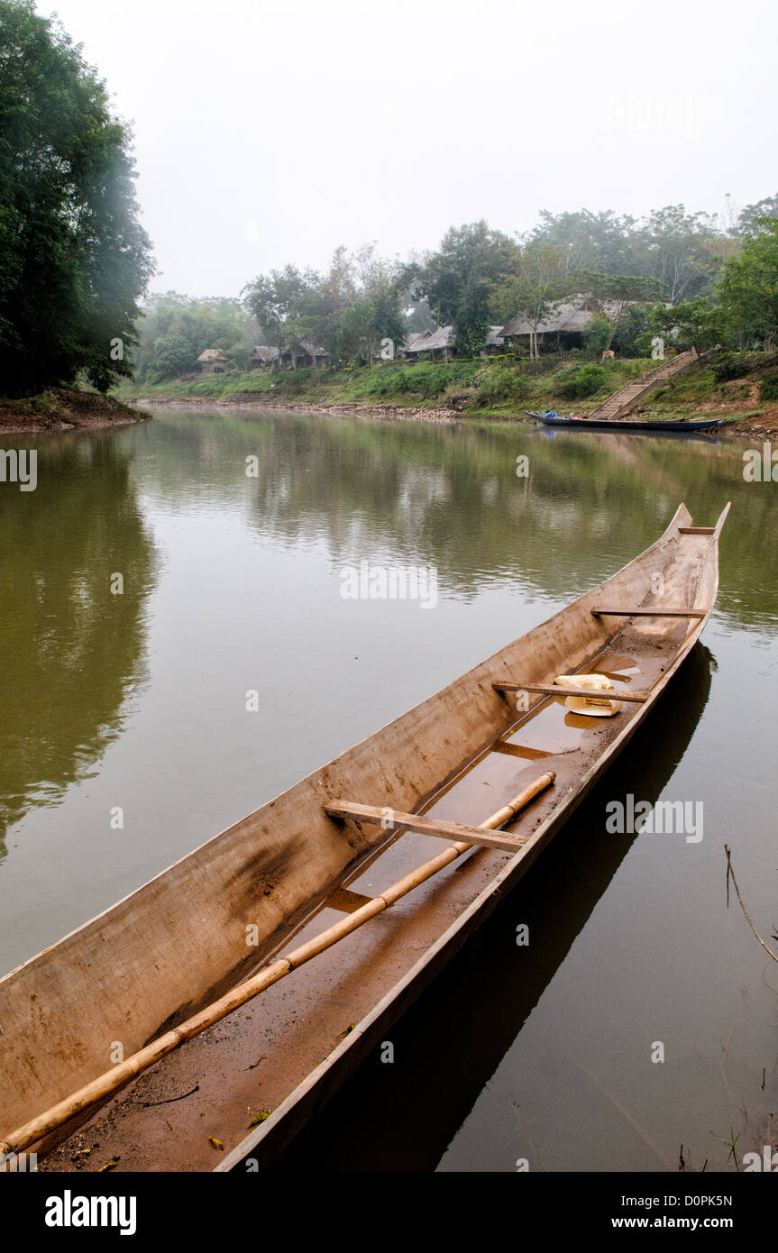Holzboot Nam Tha Fluss Luang Namtha Laos // LUANG NAMTHA, Laos — Holzboote ruhen an den Ufern des Flusses Nam Tha in Luang Namtha, Nord-Laos. Diese traditionellen Schiffe dienen als lebenswichtige Transport- und Fischereigeräte für die lokalen Gemeinden entlang der Wasserstraße. Der Fluss Nam Tha fließt durch die Provinz Luang Namtha, die an China und Myanmar im Nordwesten Laos grenzt. Die Region ist bekannt für ihre vielfältigen ethnischen Gemeinschaften und ihr bergiges Gelände. Die Stadt Luang Namtha dient als Provinzhauptstadt und Tor zum Nam Ha National Protected Area. Die Flüsse des Gebiets bleiben zentral für die lokale Region Stockfoto