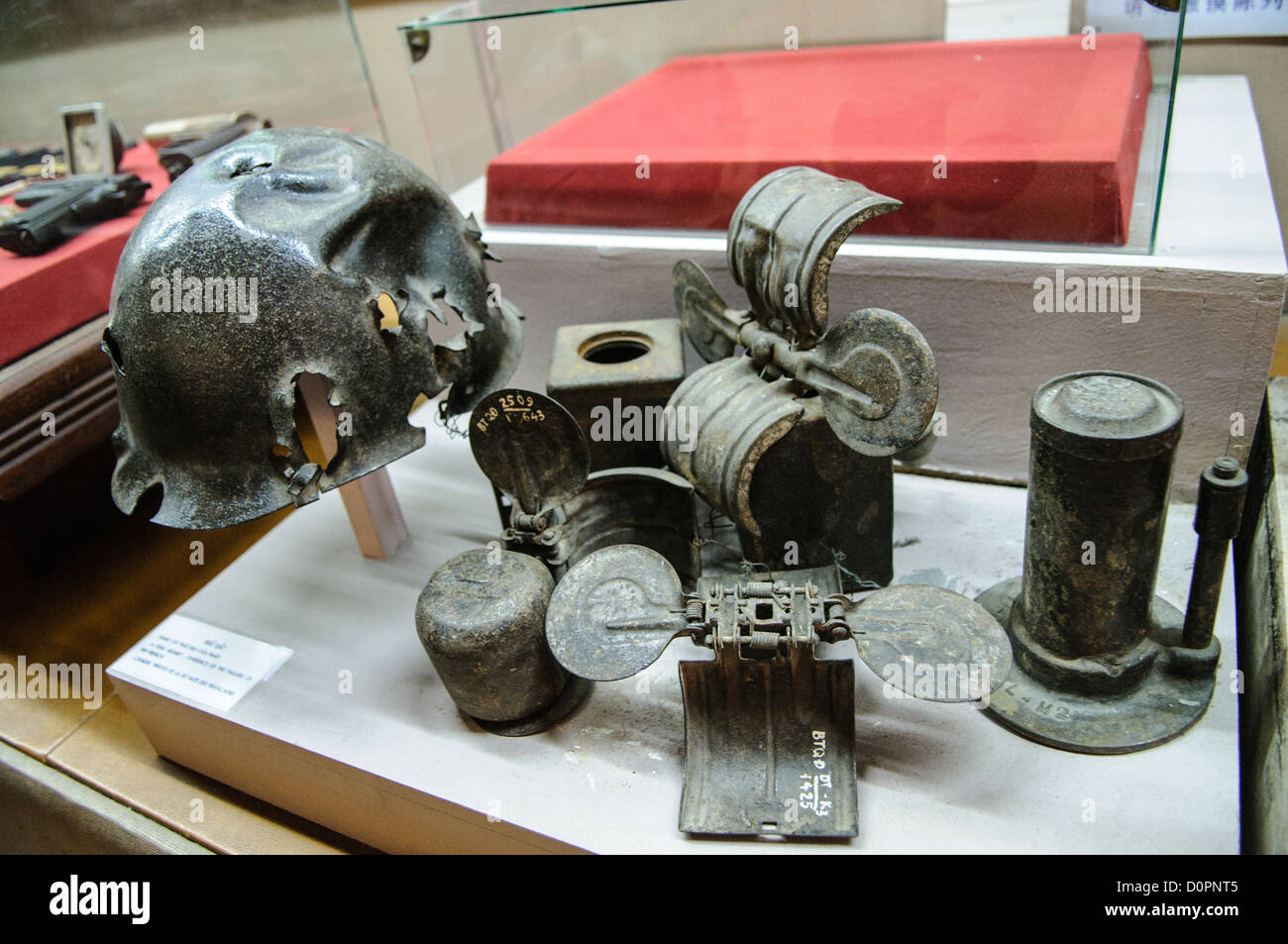 Vietnam Military History Museum Granaten Helme Hanoi // HANOI, Vietnam — Eine Vitrine im Vietnam Military History Museum zeigt verschiedene Arten von Granaten und kampfbeschädigten Helmen mit Schrapnell. Das 1956 gegründete Museum beherbergt umfangreiche Sammlungen militärischer Artefakte aus den verschiedenen Konflikten Vietnams im 20. Jahrhundert. Die Institution dient als primäres Archiv für Militärgeschichte des Landes und dokumentiert die Kriegsführung durch erhaltene Kampfmittel und Artefakte auf dem Schlachtfeld. Diese Exponate liefern physische Beweise für Kampfeinsätze und ihre Auswirkungen auf Milizen Stockfoto