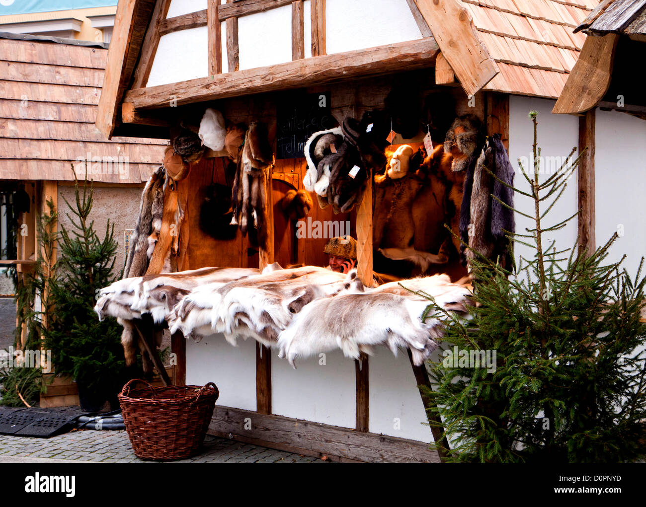 München, Deutschland. Traditionelle mittelalterliche Weihnacht (Mittelaltermarkt) am Wittelsbacher Platz in Munich.Vendor Chats Handy in einer Kabine, Verkauf von Tierfellen und Pelz-Hüte. Der mittelalterliche Weihnachtsmarkt ist ziemlich seltsam: Anbieter tragen antike Kostüme und "mittelalterlichen" Ware zu verkaufen. Stockfoto