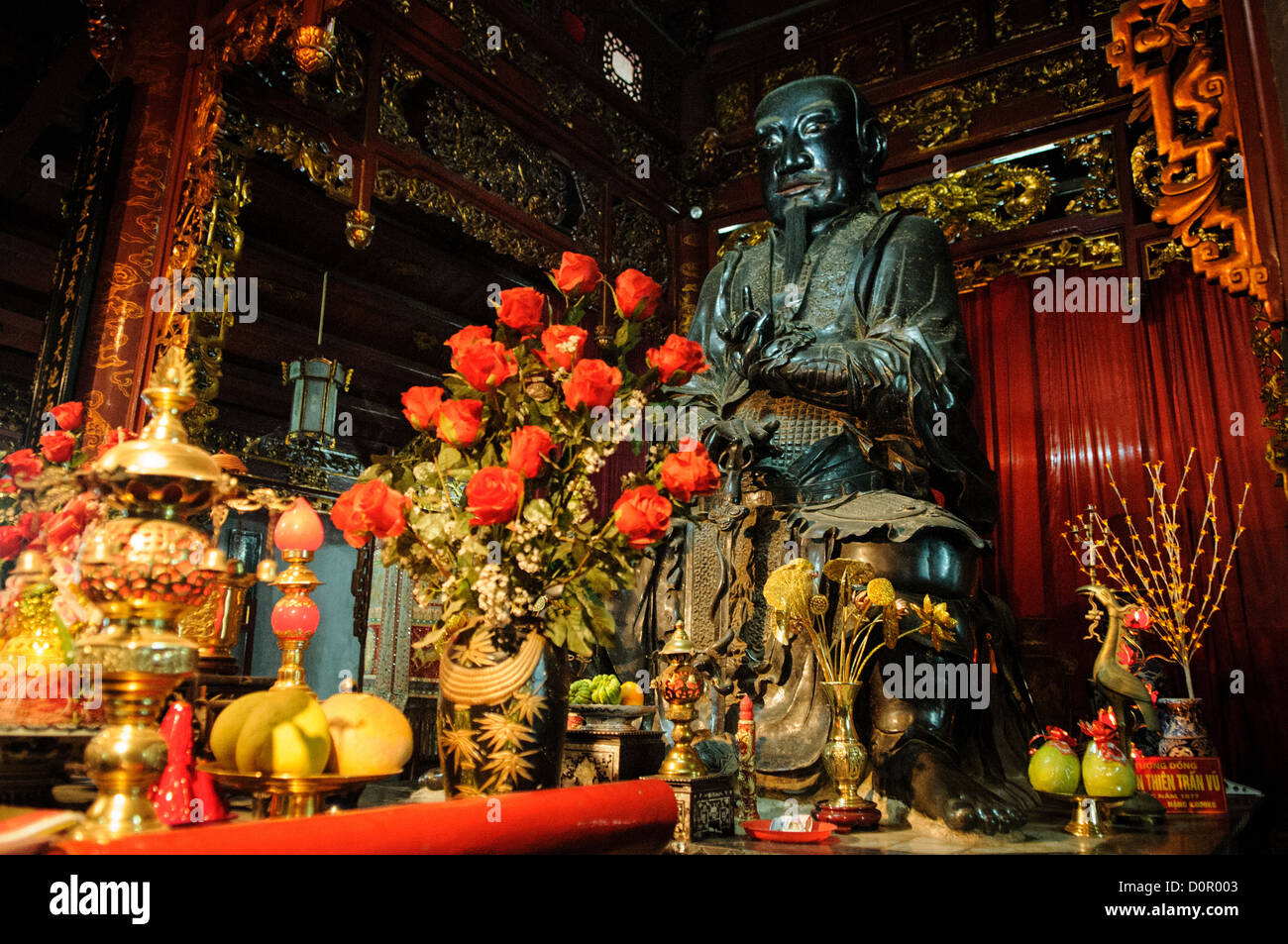 Tran Quoc Pagoda Buddhist Shrine Hanoi Vietnam // HANOI, Vietnam — ein kunstvoller buddhistischer Schrein befindet sich in einer Seitenkapelle innerhalb der Tran Quoc Pagoda auf der Goldenen Fisch-Insel im West Lake. Die dekorativen Elemente repräsentieren den traditionellen vietnamesischen buddhistischen künstlerischen Stil und religiösen Symbolismus. Dieser Andachtsraum dient weiterhin seinem ursprünglichen Zweck innerhalb eines der ältesten buddhistischen Tempel Vietnams. Stockfoto