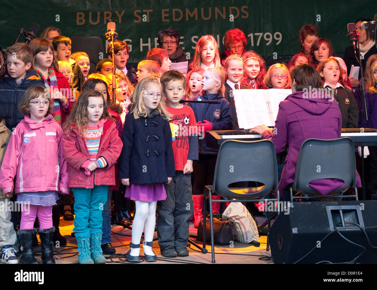Kinder in einer Grundschule Chor singen, auf der Bühne im Weihnachtsmarkt, Bury St. Edmunds, Suffolk UK Stockfoto
