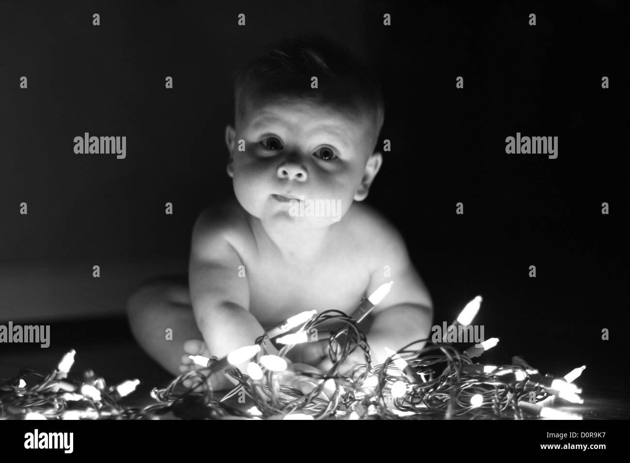 Baby spielt mit Weihnachtsbeleuchtung Stockfoto