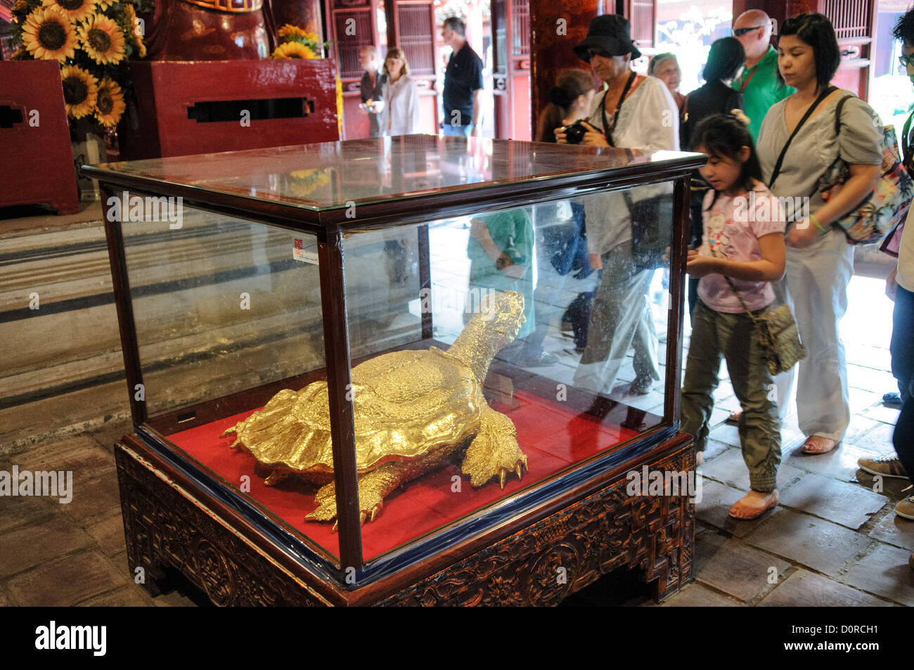 HANOI, Vietnam – Besucher sehen eine Goldschildkröte, eines der heiligen Symbole von Hanoi, im Tempel der Literatur in Hanoi. Der Tempel wurde 1070 erbaut und ist einer von mehreren Tempeln in Vietnam, die Konfuzius, Weisen und Gelehrten gewidmet sind. Stockfoto