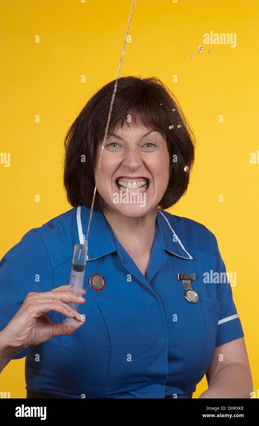 Porträt einer Krankenschwester entblößte ihre Zähne und eine Spritze Spritzen. Stockfoto