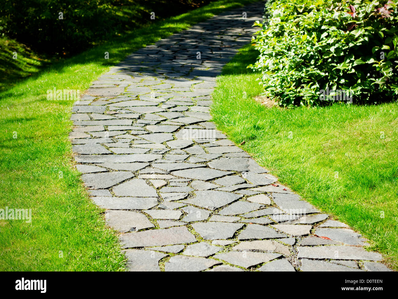 Gartenweg mit Naturstein in einem herbstlichen Garten gepflastert