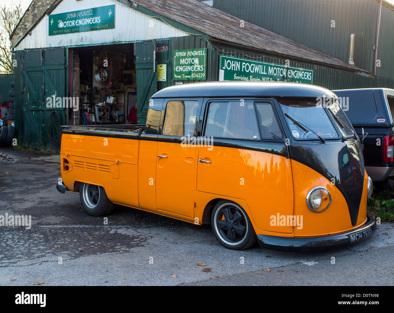 Bovey Tracey, Devon, England. 29. November 2012. Ländliche Garage und Vorplatz mit bunten Volkswagen Pickup-Truck. Stockfoto