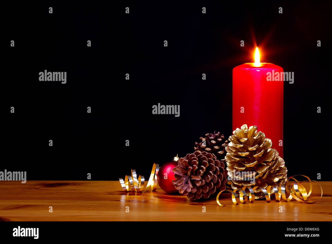 Still-Leben Foto einer Weihnachten Kerze brennt hell mit gold Tannenzapfen und Band plus eine rote Kugel Stockfoto