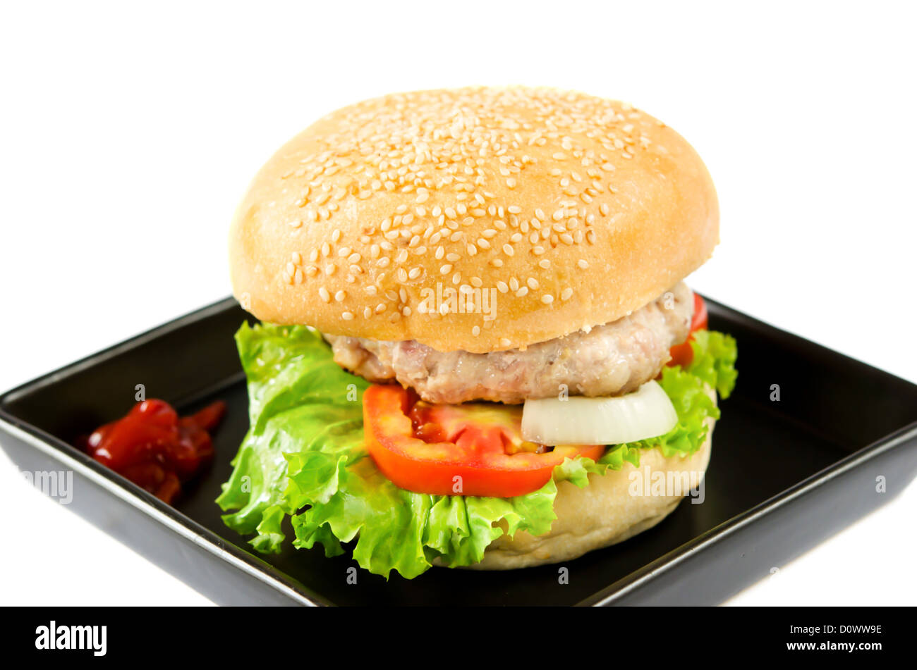 Hamburger mit Tomatensauce auf schwarzem Teller Stockfoto