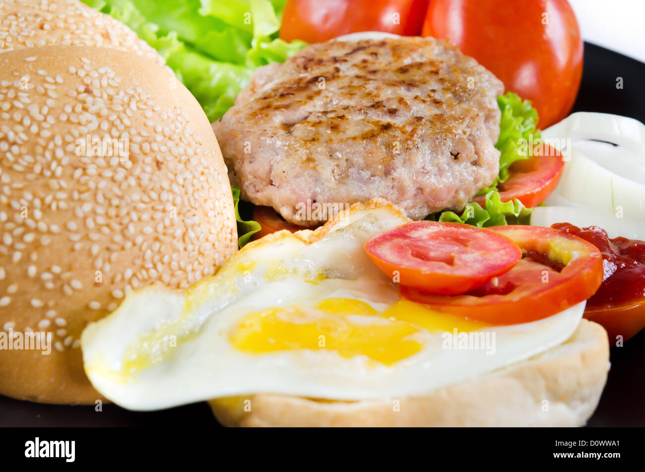 reichhaltiges Frühstück mit Spiegeleiern und frischem Gemüse, Brot, gebratenes Schweinefleisch Stockfoto