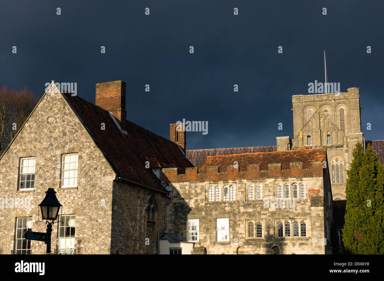 Gebäude rund um Winchester Cathedral durch tiefstehende Sonne dunkel bewölkten Himmel beleuchtet Stockfoto