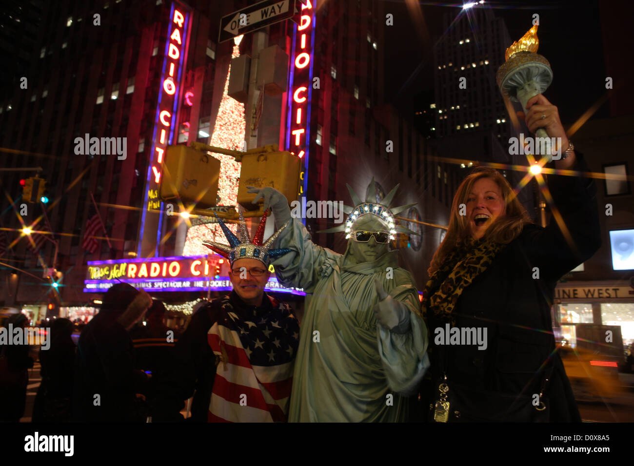 Touristen posieren mit einer Statue of Liberty street Busker zur Weihnachtszeit auf der 6th Avenue, Manhattan, New York USA. Stockfoto