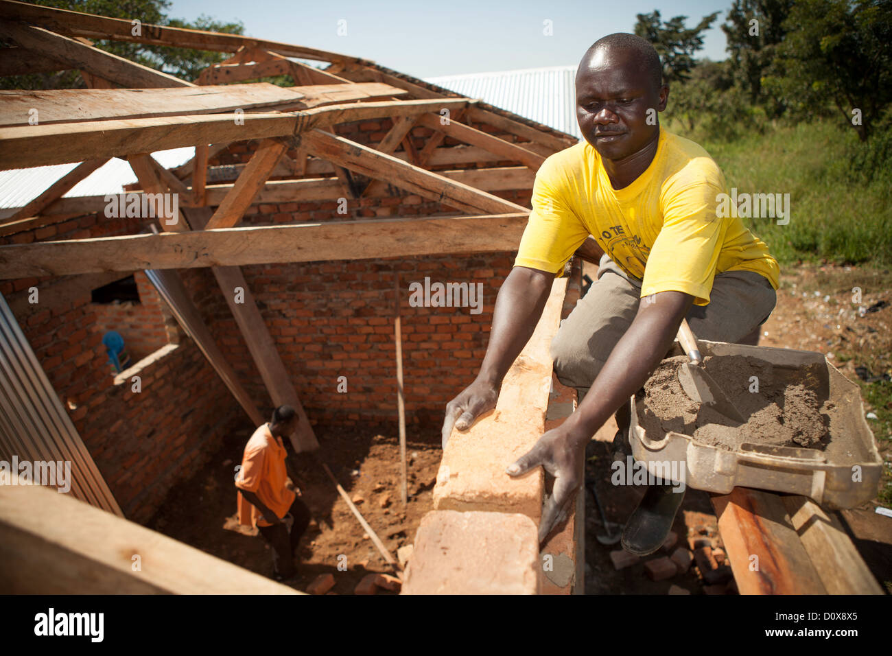 Ein Bauarbeiter hilft beim Aufbau einer Schule im ländlichen Uganda, Ostafrika. Stockfoto