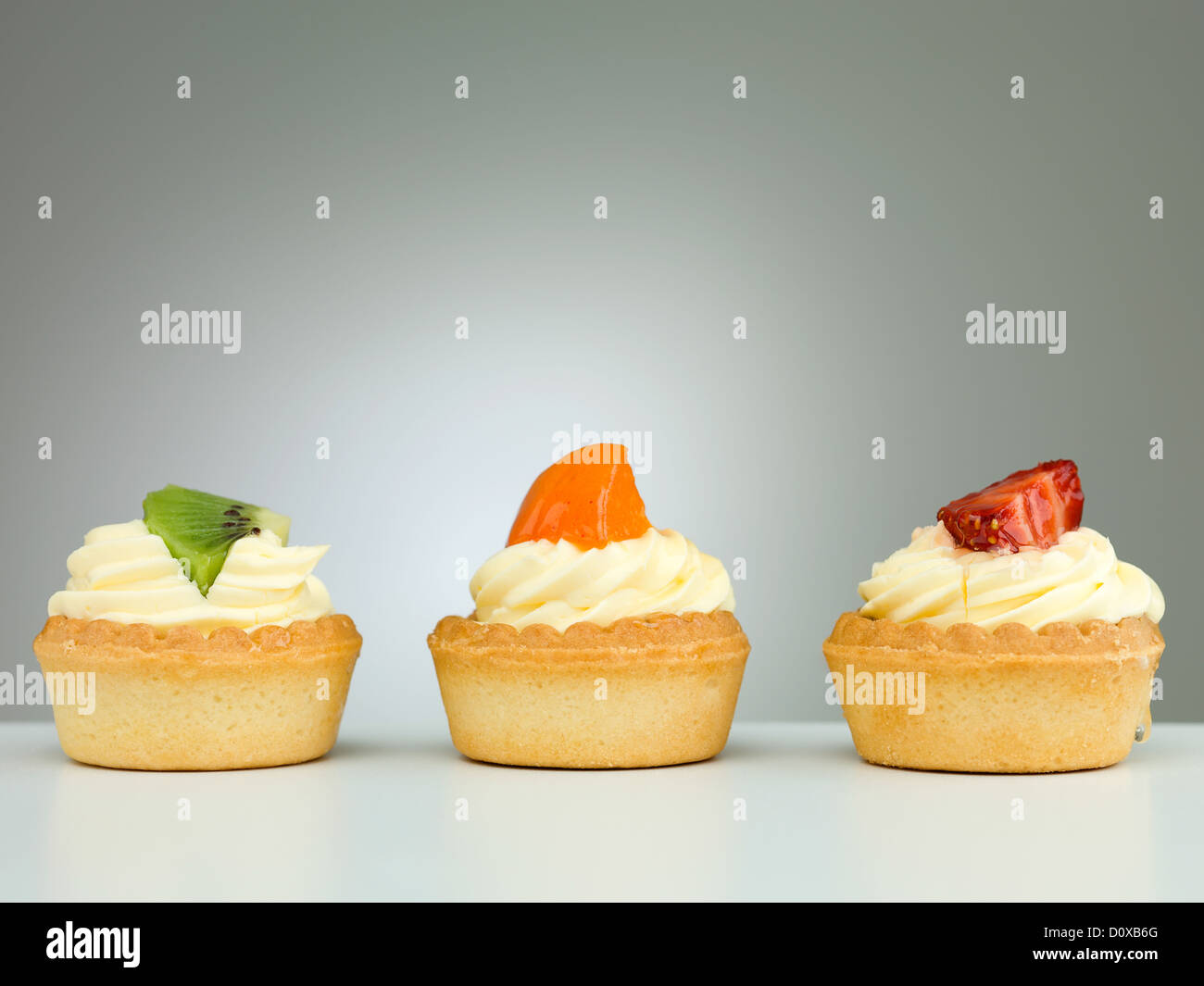 drei köstliche Torten mit Apricot Kiwi Erdbeer neutralen Hintergrund mit Abstufung Stockfoto
