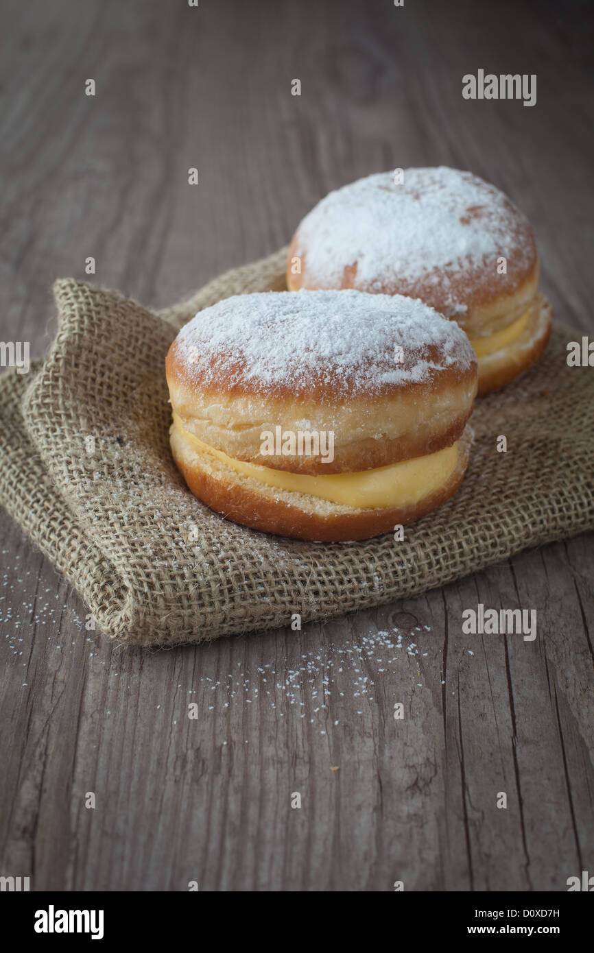 Köstliche Krapfen mit Sahne auf einem hölzernen Hintergrund Stockfoto