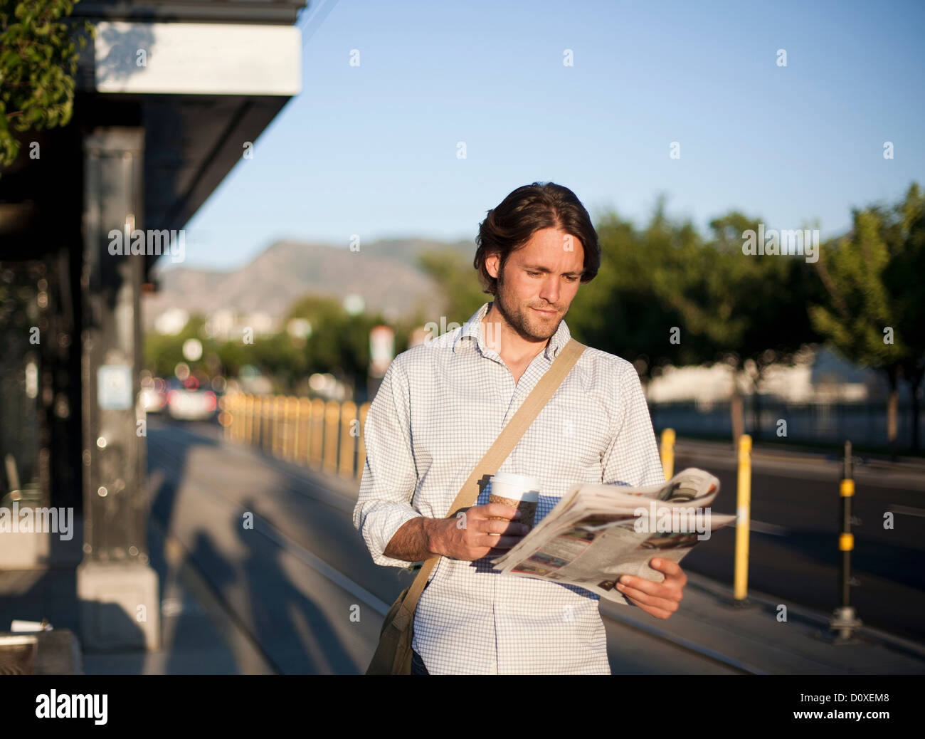 Mann liest Zeitung am Bahnhof Stockfoto