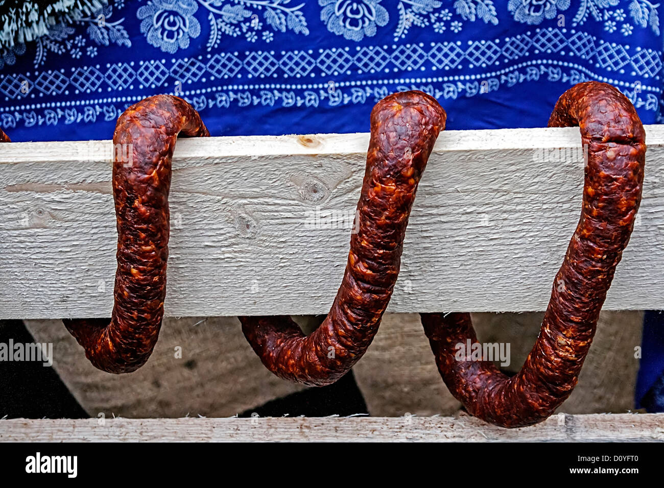 Geräucherte Würste und biegen Sie die Schlange durch ein Stück Holz geprägt. Ornamentale Anordnung. Stockfoto