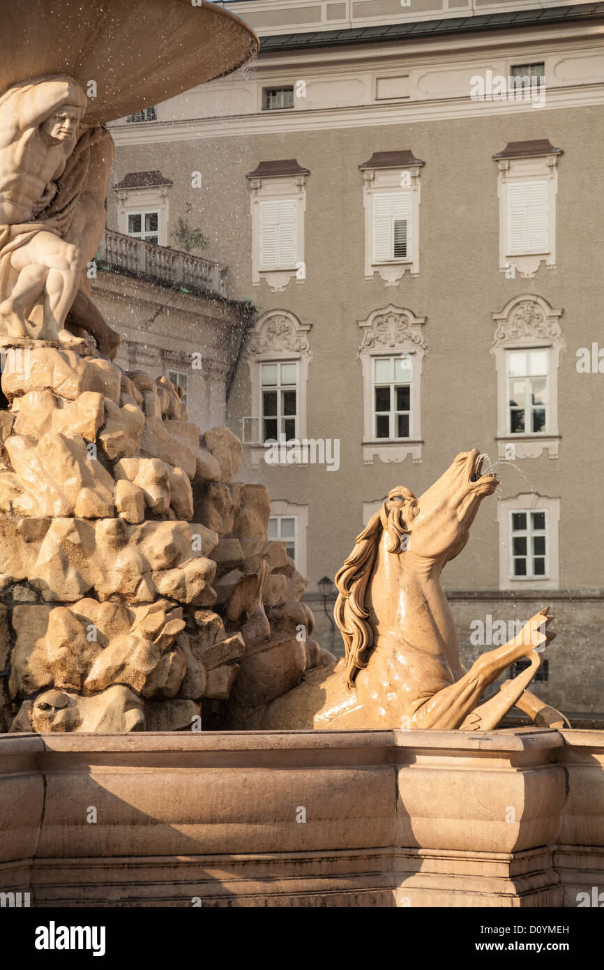 Ein Pferd Detail aus der Salzburger Residenzplatz Barockbrunnen, mit den dekorativen Fenstern der Alte Residenz dahinter. Stockfoto