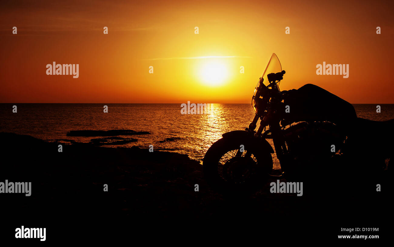 Bild von Luxus Motorrad am Strand in der Nacht, Silhouette der Motorrad am Sonnenuntergang, Harley Davidson, aktives Leben Stockfoto