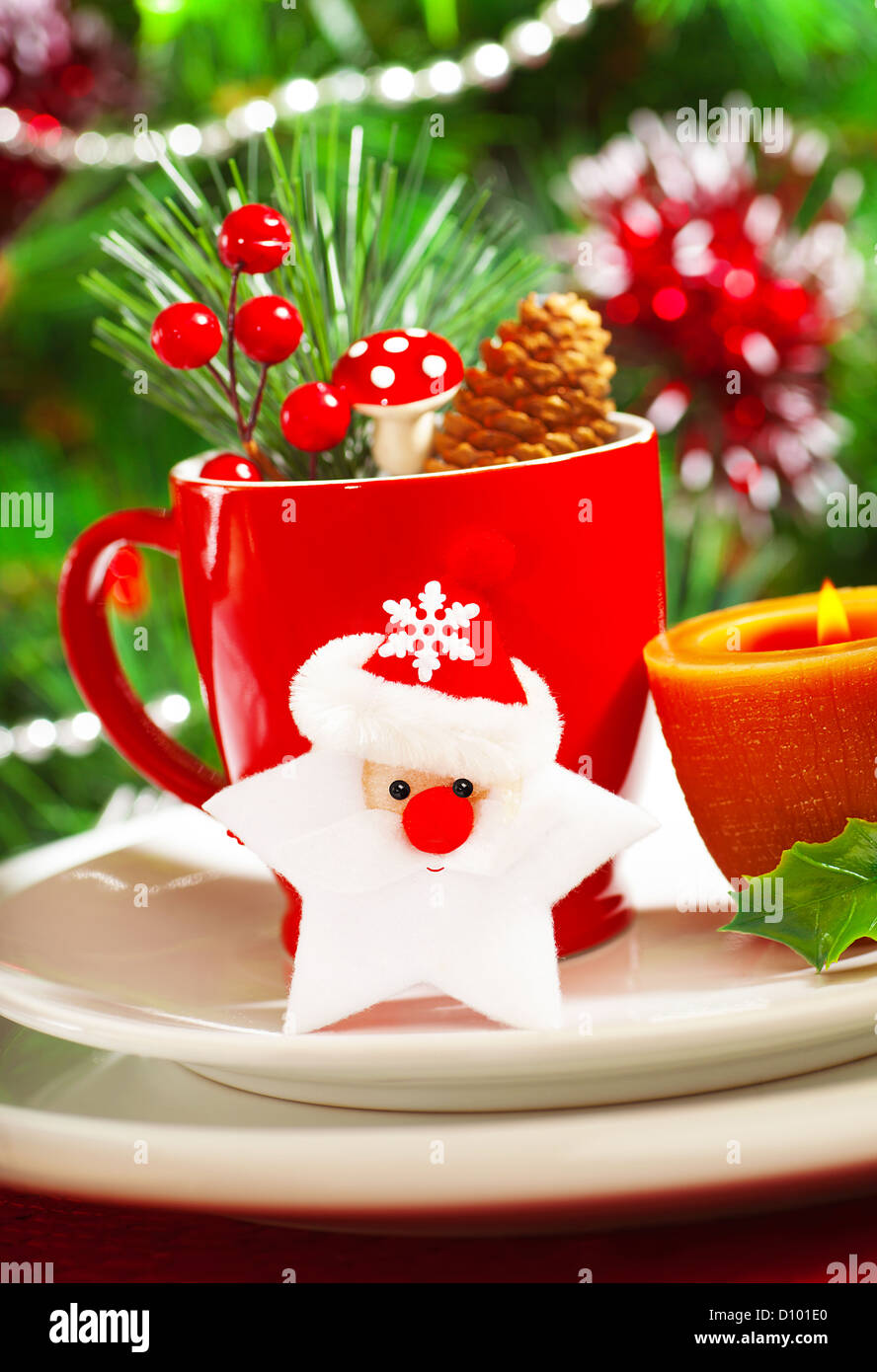 Bild von Luxus Weihnachten Tisch Dekoration, rote Kaffeetasse verziert mit Santa Claus Sterne, gelbe Kerze und Beere Zweig Stockfotografie