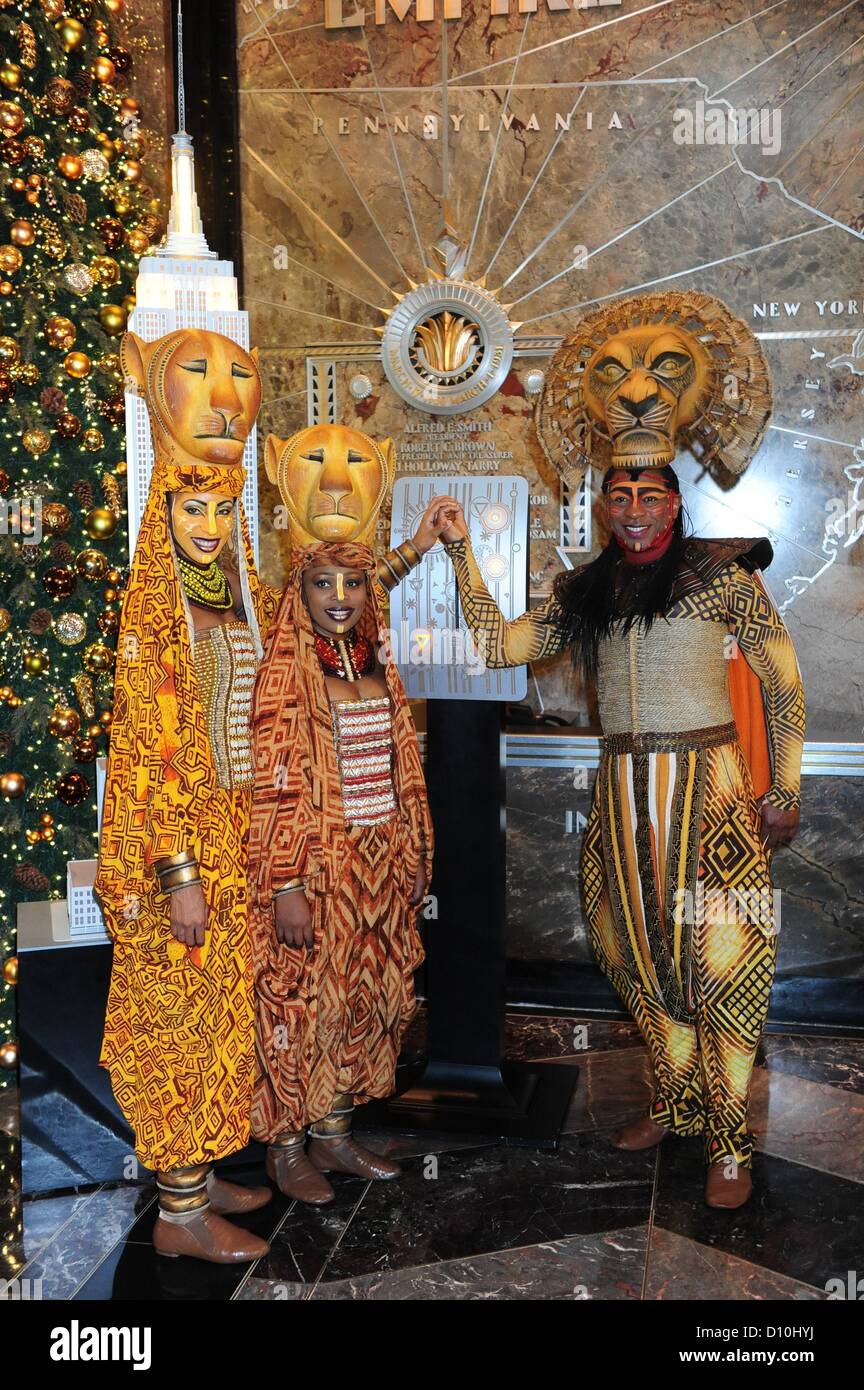 Manhattan, New York, USA - ALTON FITZGERALD weiß wie Mufasa vom Broadway The Lion King zusammen mit Löwinnen Lindiwe Dlamini und Chondra La-Tease Gewinn Licht das Empire State Building gelb zur Feier von 15 Jahren am Broadway, Dienstag, 4. Dezember 2012. Stockfoto