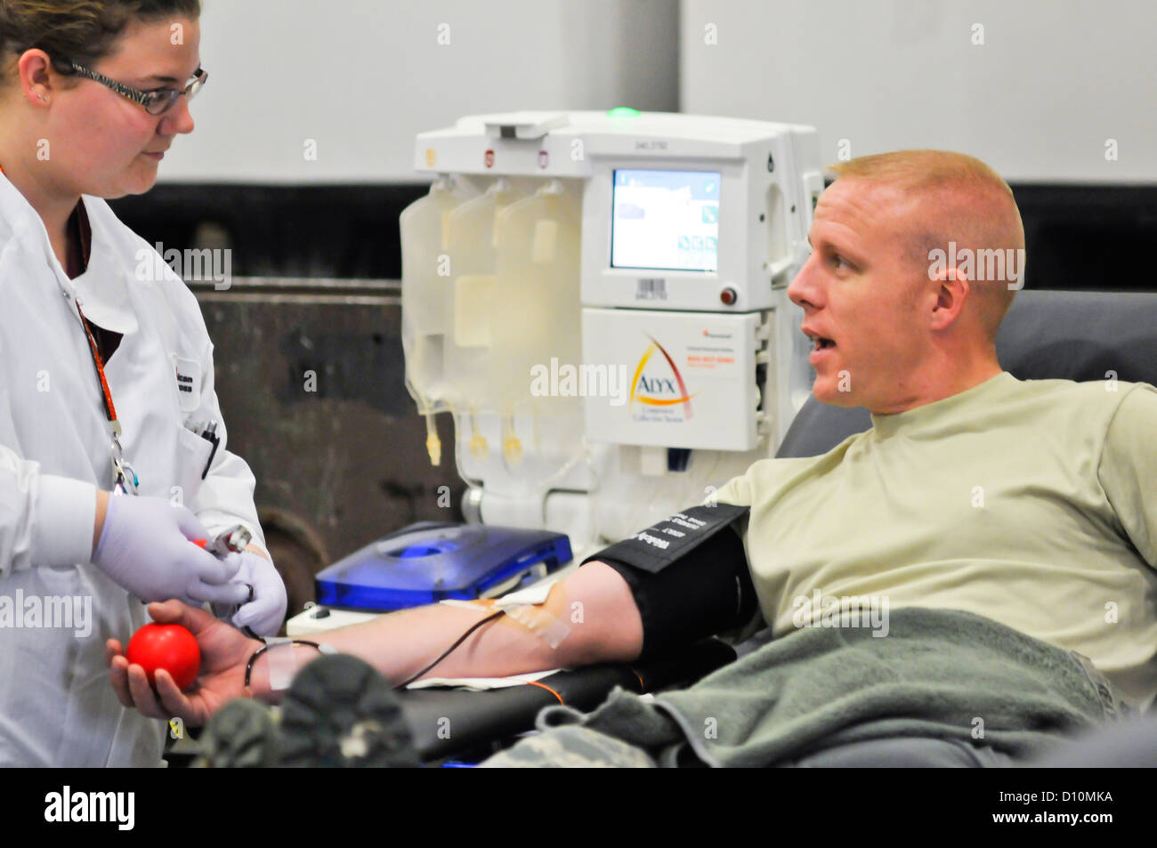 Ein Flieger des 182. Airlift-Flügels in Peoria, Illinois, berät einen Phlebotomisten während einer Blutfahrt, die vom amerikanischen Roten Kreuz organisiert wird, um andere Flieger zu unterstützen. Stockfoto