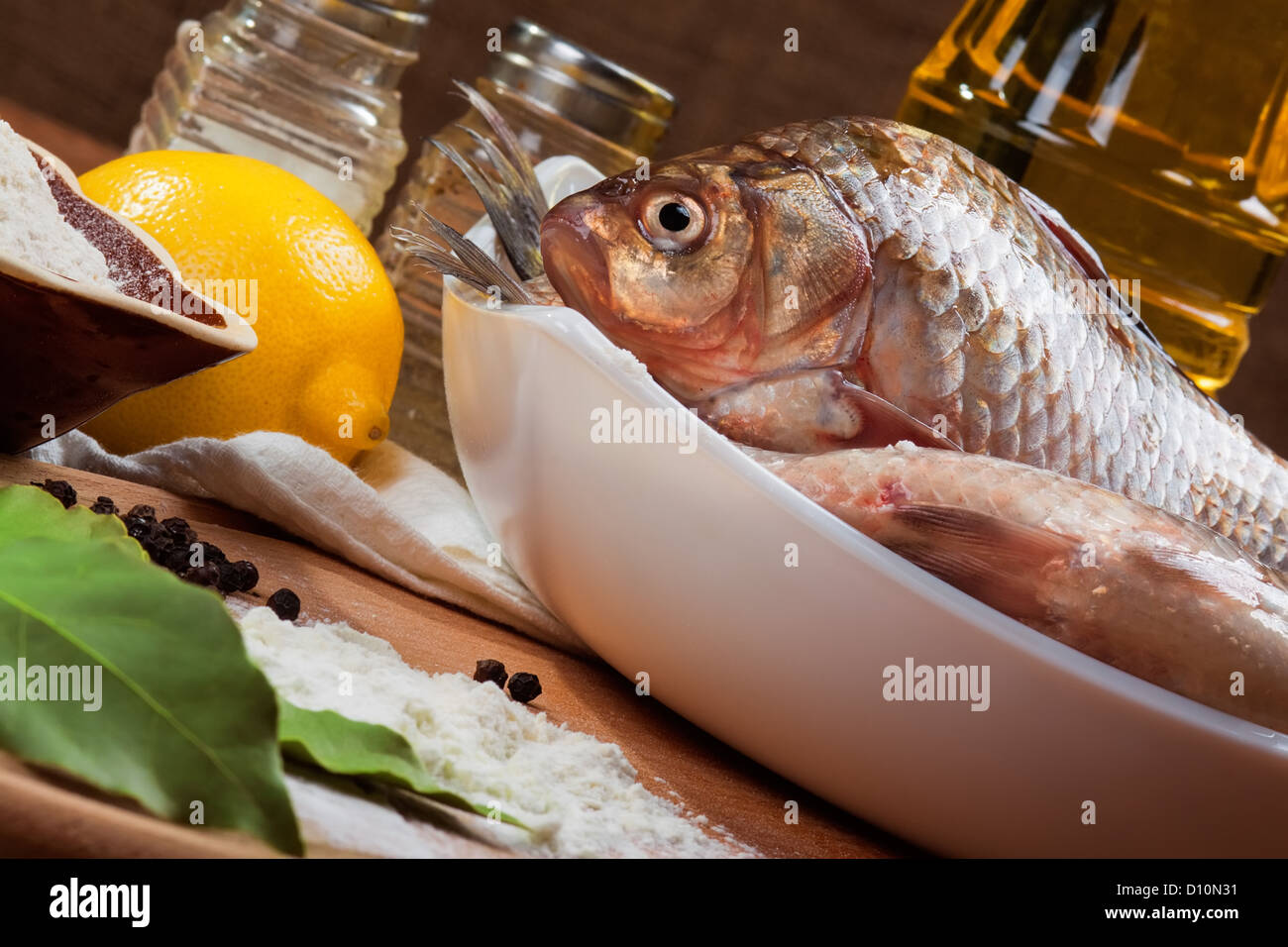 Frische Karpfen auf einem Küchentisch mit Zitrone und Mehl Stockfoto