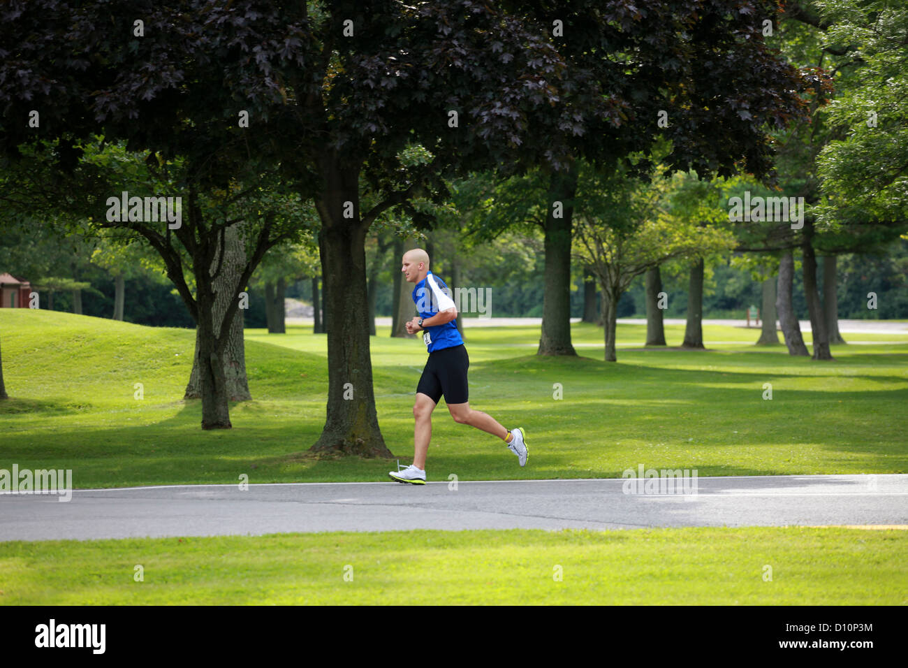 Athlet läuft durch den Park bei einem Triathlon. Stockfoto